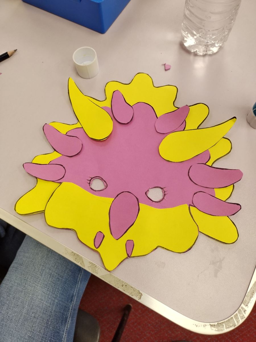 a yellow and pink triceratops mask