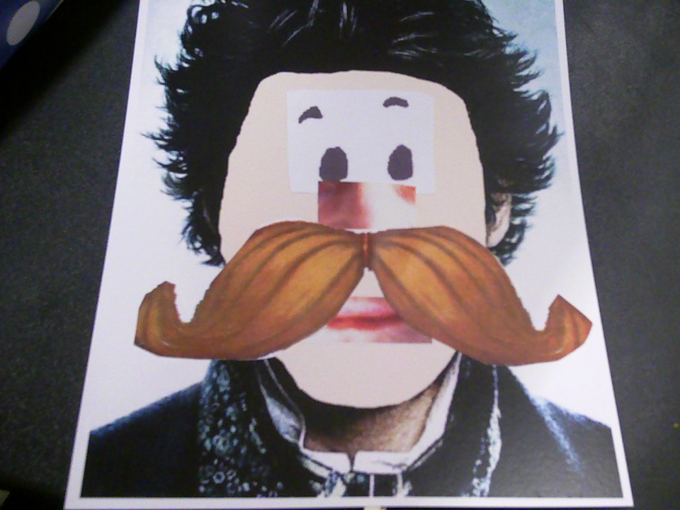 Pictures of facial features glued to a picture of a faceless head with black hair