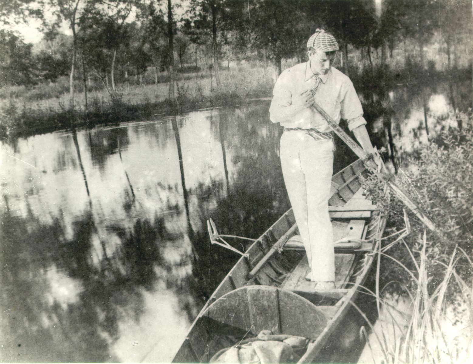 Sidney Paget in a deerstalker hat standing in a rowing boat pushing away from the shore with an oar