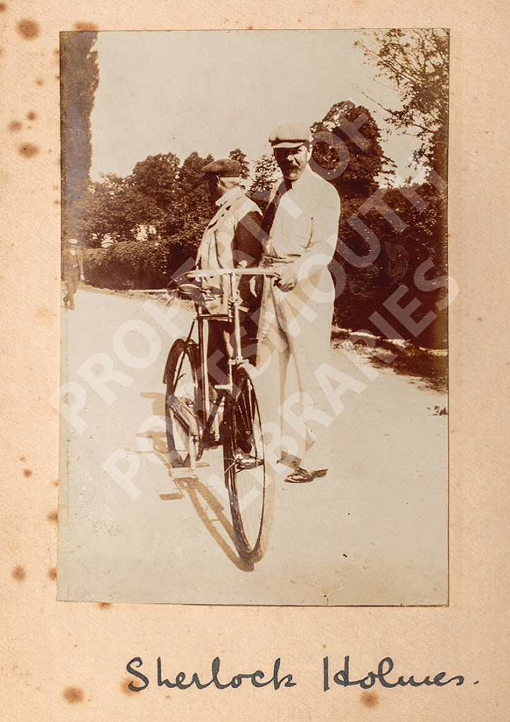 A postcard showing Conan Doyle and another man with a bicycle with the words Sherlock Holmes written underneath